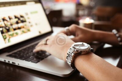 A person is using their laptop while wearing a watch.